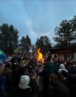 Рождественская сценография на Златиборе: украшенная церковь и большое пламя рождественской елки, согревающее собравшихся верующих.
