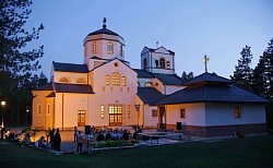 Великолепная архитектура храма Преображения Господня в Златиборе ночью под профессиональным декоративным освещением, которое подчеркивает белые фасадные стены и контуры церкви на фоне темного горного неба и окружающих освещенных дорожек.